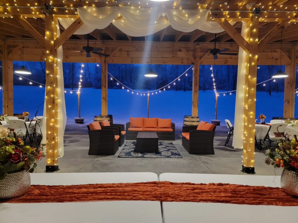 Warmly lit timber frame barn overlooking a snow-covered landscape at Timber Valley Farm Barn Rental, showcasing a welcoming Snow Wedding Venue Maryland in winter.