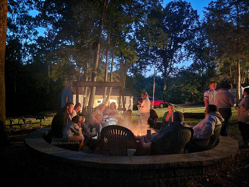 Family and friends gather around a campfire during a wedding weekend at Timber Valley Farm Barn Rental, enjoying on-site wedding lodging in Clear Spring, Maryland.