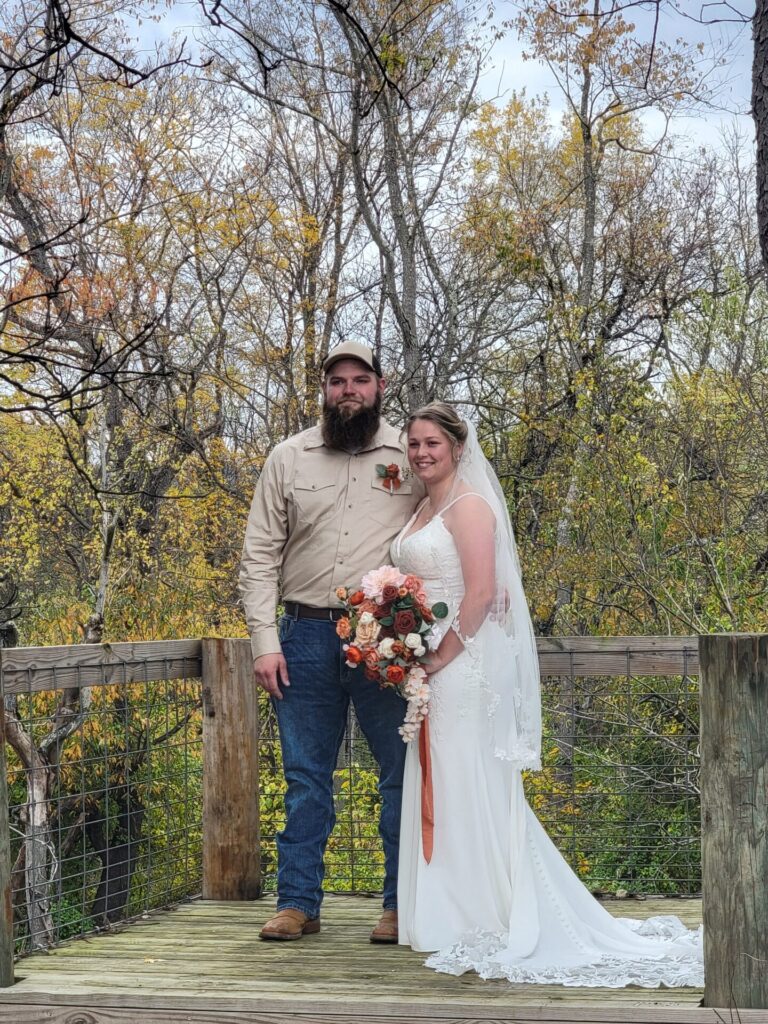 Bride and groom standing on the Timber Valley Railroad Overlook surrounded by beautiful autumn scenery at Timber Valley Farm Barn Rental in Clear Spring, Maryland.