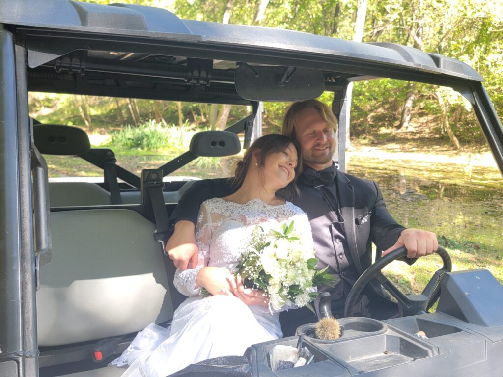 Bride and groom enjoying a Bobcat UTV ride through the scenic woodlands at Timber Valley Farm Barn Rental in Clear Spring, Maryland.