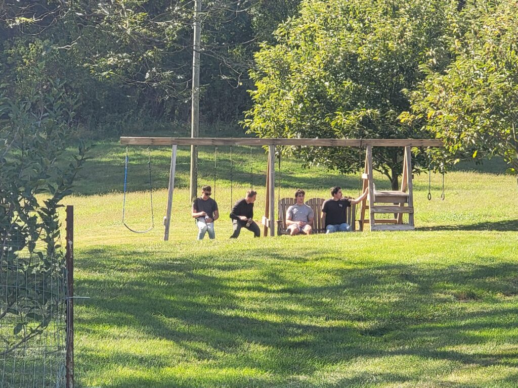 Family and friends relaxing on the swings before the wedding at Timber Valley Farm Barn Rental during a Wedding Rehearsal Day.