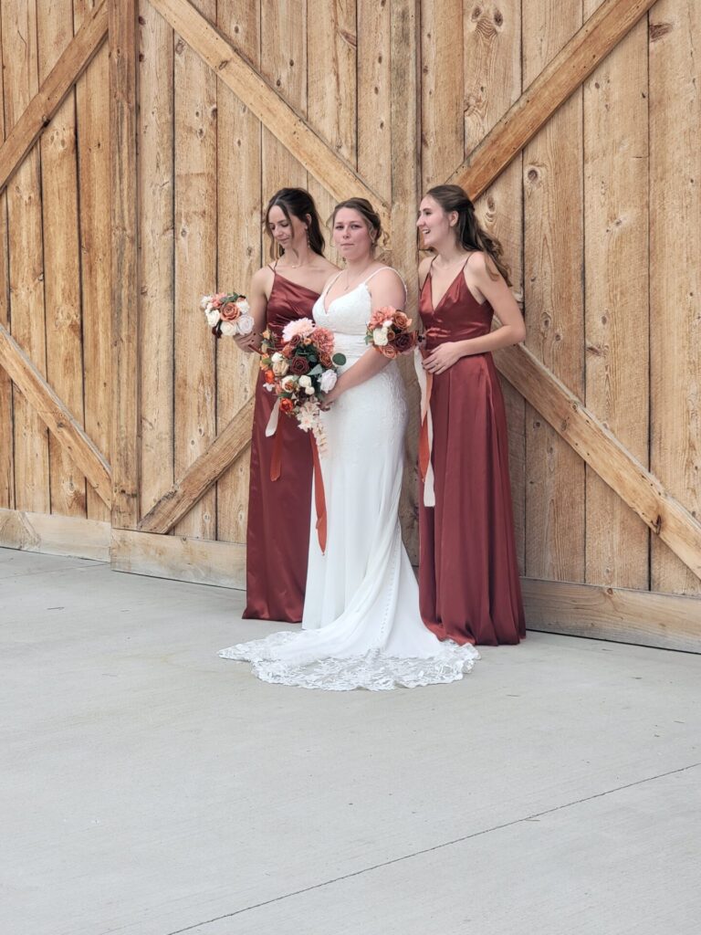 Bride and bridesmaids posing in front of the handcrafted wooden barn doors at Timber Valley Farm Barn Rental in Clear Spring, Maryland.