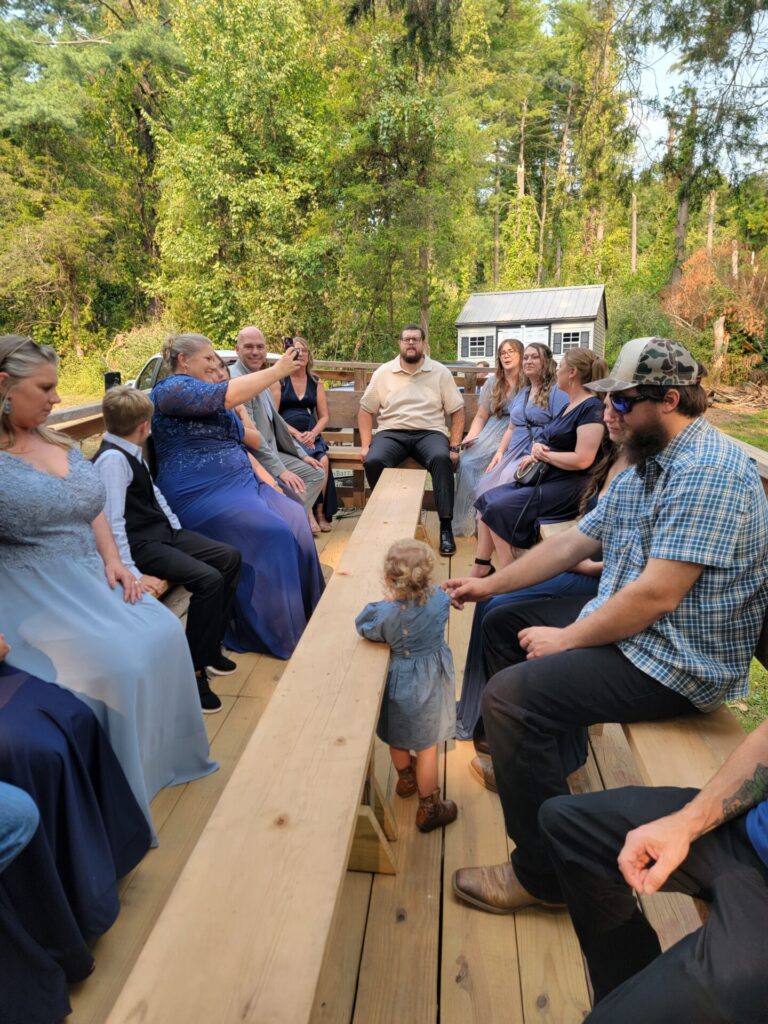 Wedding party riding on the Timber Valley Trailblazer wagon from Timber Valley Retreat to Timber Valley Farm Barn Rental in Clear Spring, Maryland.
