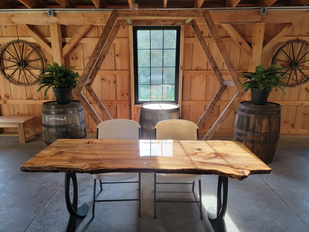 Handcrafted Live Edge Sweetheart Table inside the timber-frame barn at Timber Valley Farm Barn Rental showing the natural wood grain and live edge design before wedding decorations are added.