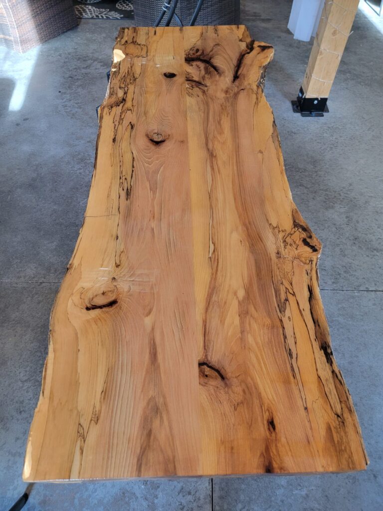 Close-up of a handcrafted live edge sweetheart table showing the unique wood grain, natural knots, and live edge craftsmanship at Timber Valley Farm Barn Rental.