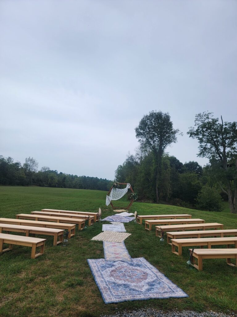Hexagon Wedding Ceremony Backdrop with floral decorations and wooden benches at Timber Valley Farm Barn Rental in Clear Spring, Maryland.
