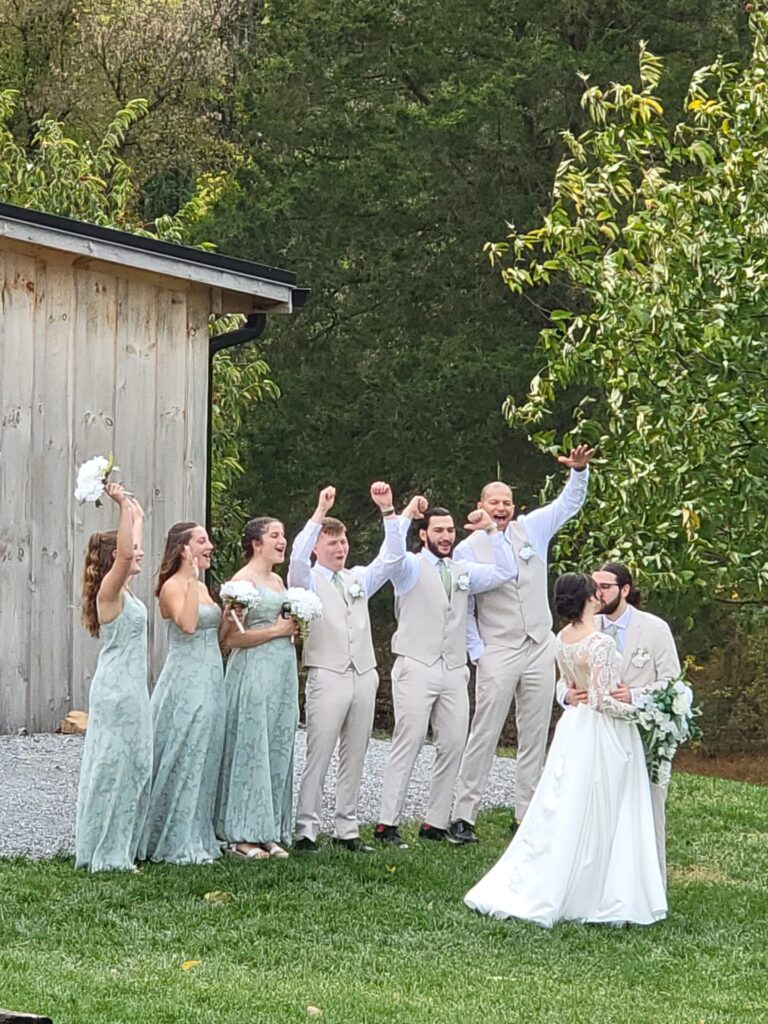 Wedding Ceremony Tips featuring the bride and groom celebrating with their wedding party during outdoor wedding portraits at Timber Valley Farm Barn Rental in Clear Spring, Maryland.