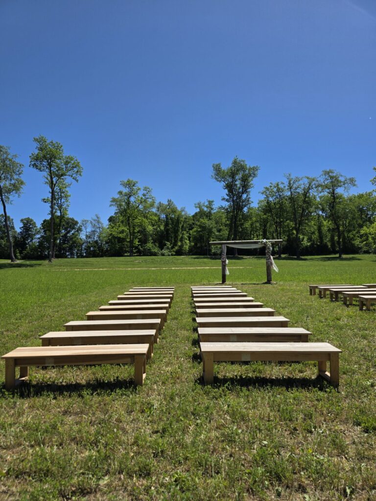 Outdoor Wedding Seating featuring handcrafted wooden benches and the Wedding Ceremony Arbor at Timber Valley Farm Barn Rental in Clear Spring, Maryland.