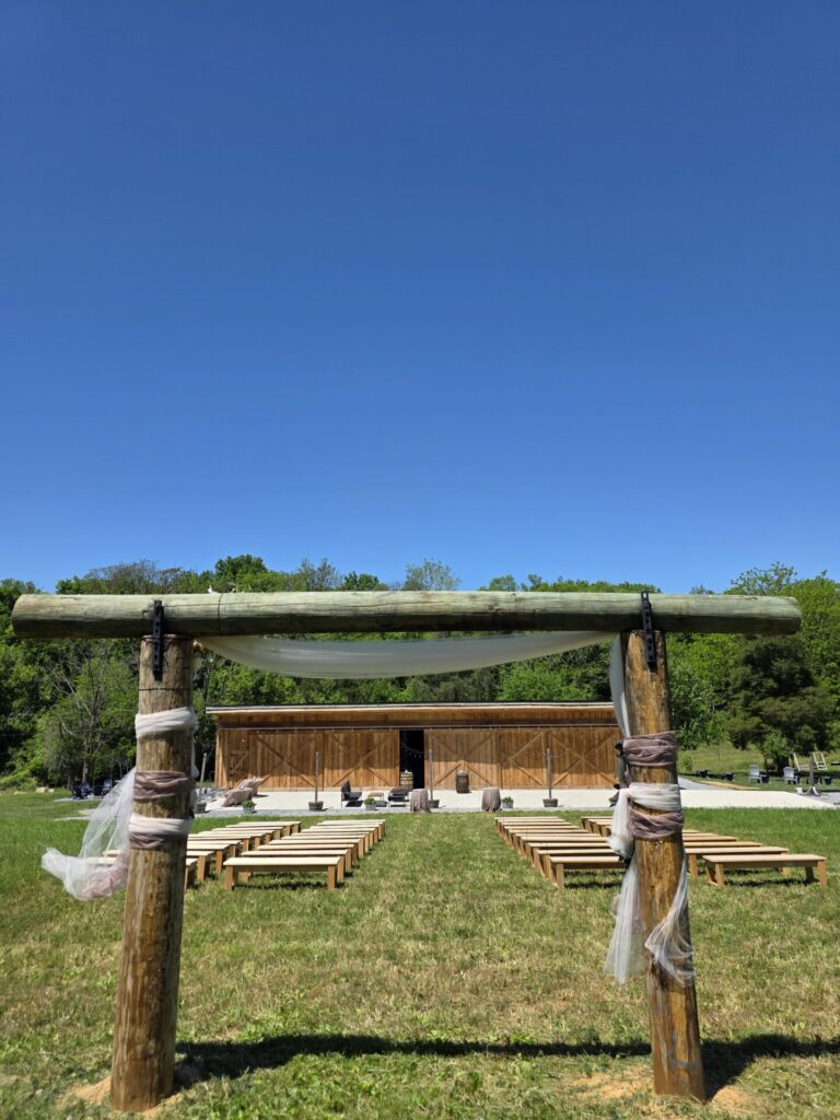 Outdoor Wedding Ceremony Ideas. Decorated handcrafted timber wedding arbor with flowing fabric and greenery at Timber Valley Farm Barn Rental in Clear Spring, Maryland.