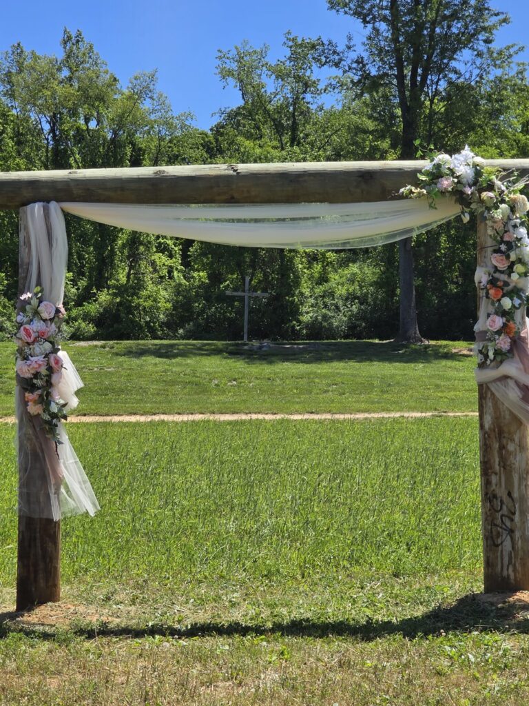 Decorated Wedding Ceremony Arbor with flowing fabric and floral arrangements overlooking the outdoor ceremony site at Timber Valley Farm Barn Rental in Clear Spring, Maryland.