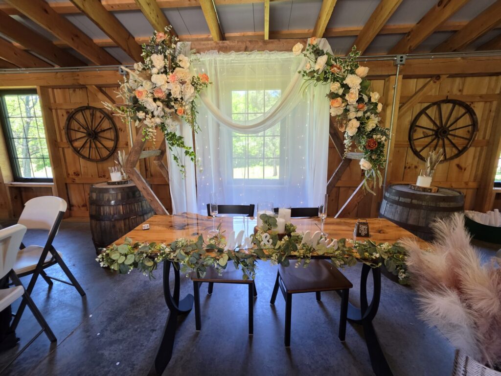Wedding Reception Ideas featuring a beautifully decorated head table inside the handcrafted timber frame barn at Timber Valley Farm Barn Rental in Clear Spring, Maryland.