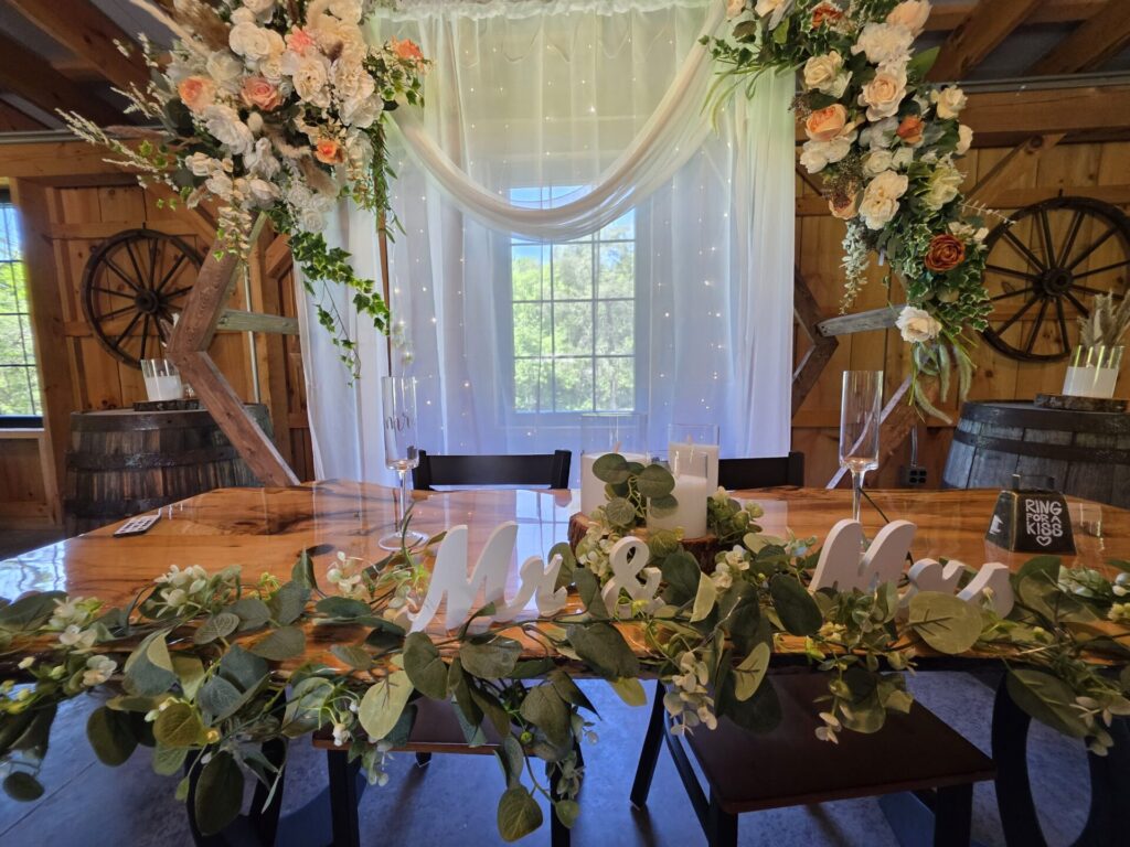 Wedding Reception Tables featuring a beautifully decorated sweetheart table with a Mr. & Mrs. sign inside the handcrafted timber frame barn at Timber Valley Farm Barn Rental in Clear Spring, Maryland.