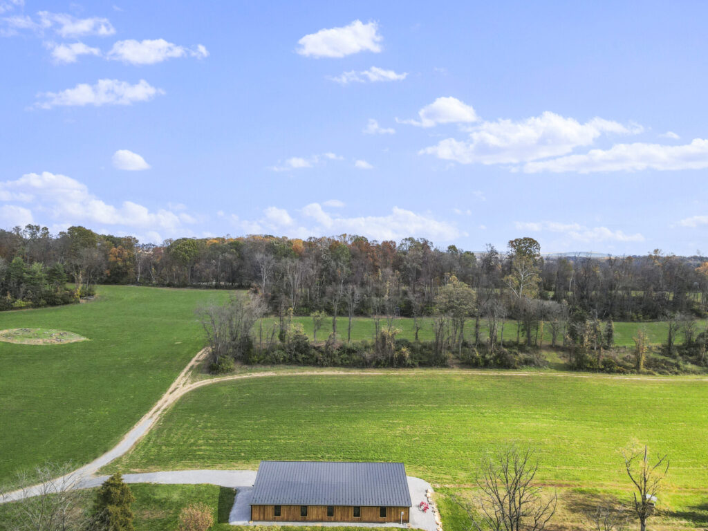 Aerial view of Timber Valley Farm Barn Rental surrounded by open green fields, wooded areas, farm lanes, and Western Maryland countryside in Clear Spring Maryland.