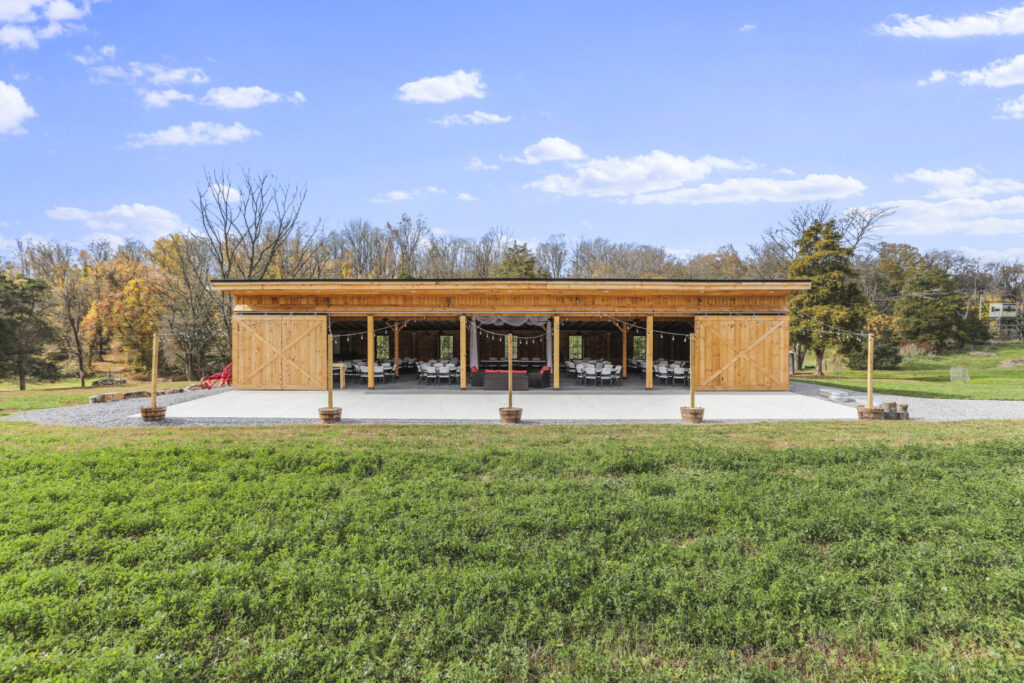 Outdoor wedding reception venue in Maryland with timber-frame barn, spacious patio, lawn, trees, and open countryside at Timber Valley Farm Barn Rental