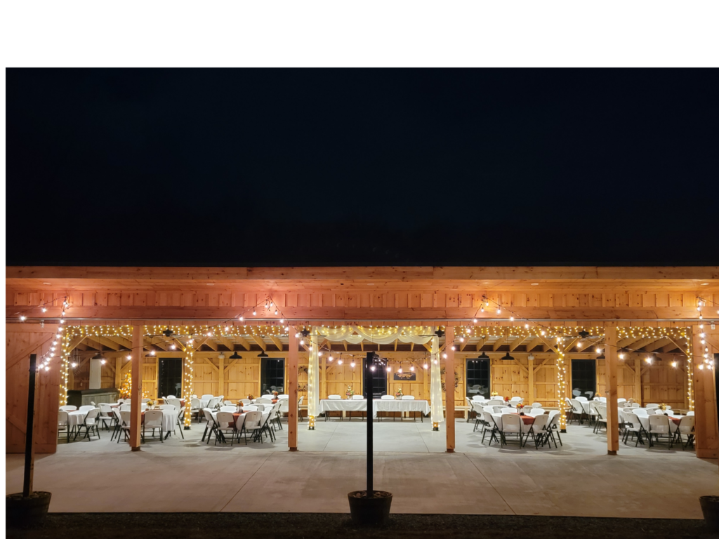 Outdoor wedding reception Maryland at night with timber-frame barn, tables, chairs, and glowing string lights at Timber Valley Farm Barn Rental