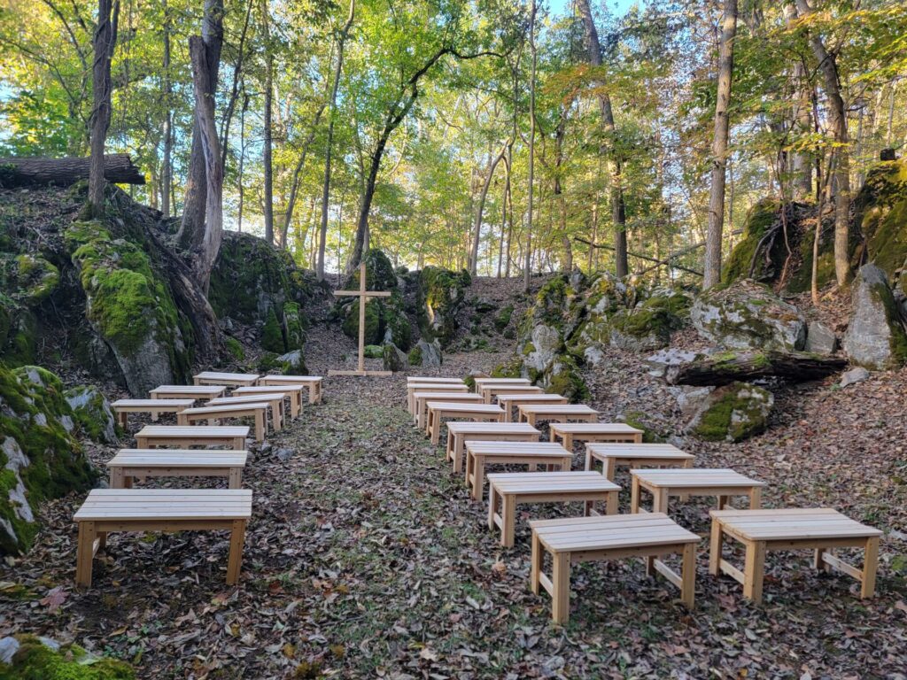 Outdoor wedding ceremony site in God's Cathedral with wooden benches prepared for a wedding ceremony at Timber Valley Farm Barn Rental in Clear Spring, Maryland.