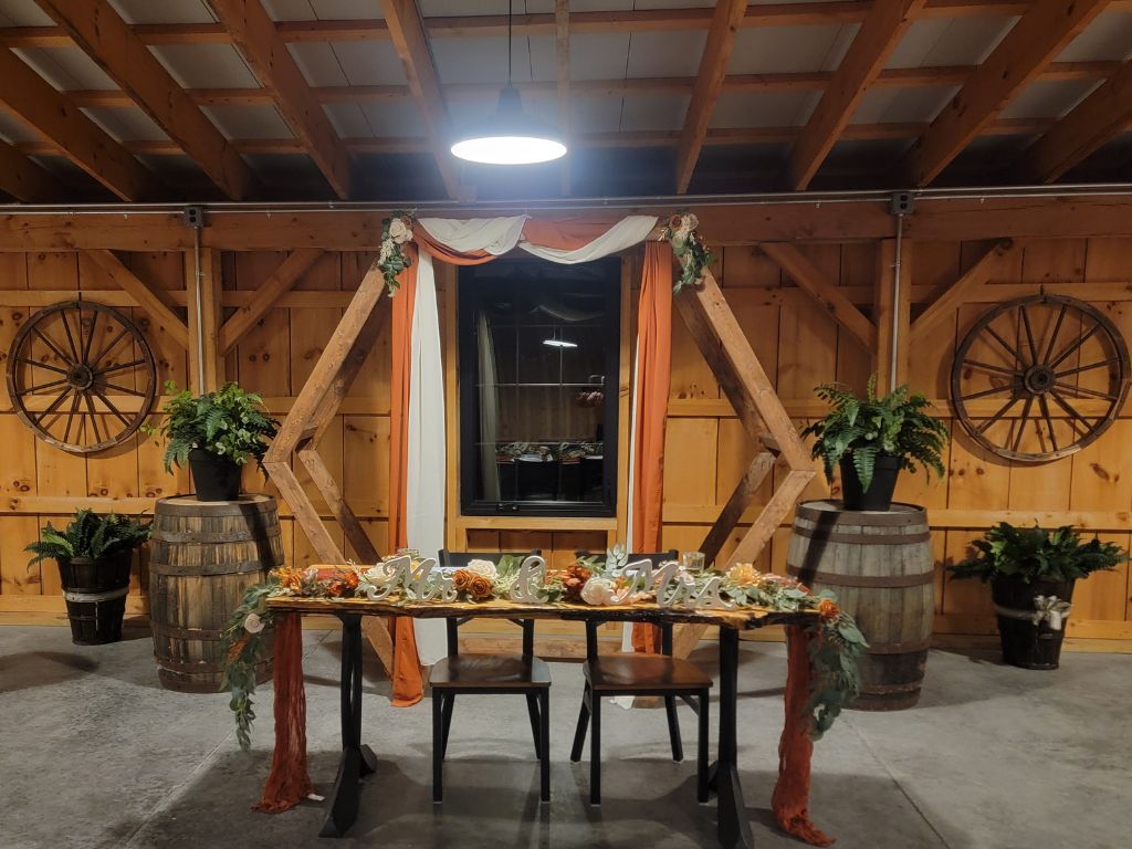 Fall-themed Hexagon Wedding Backdrop with rust-colored draping and a handcrafted Live Edge Sweetheart Table inside the timber-frame barn at Timber Valley Farm Barn Rental in Clear Spring, Maryland.