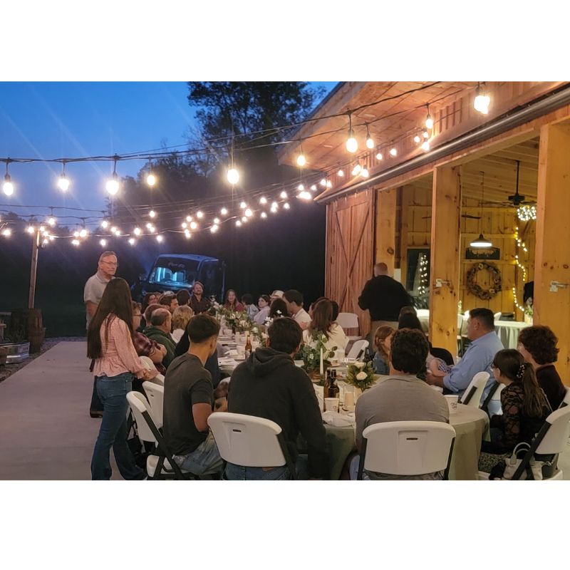 Outdoor wedding reception with guests seated at tables beside the timber-frame barn at Timber Valley Farm Barn Rental in Clear Spring Maryland