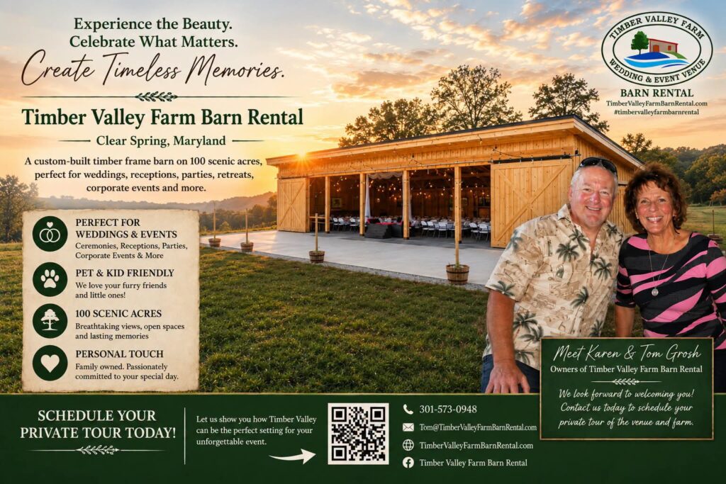 Karen and Tom Grosh standing in front of Timber Valley Farm Barn Rental with the timber-frame barn and scenic countryside behind them