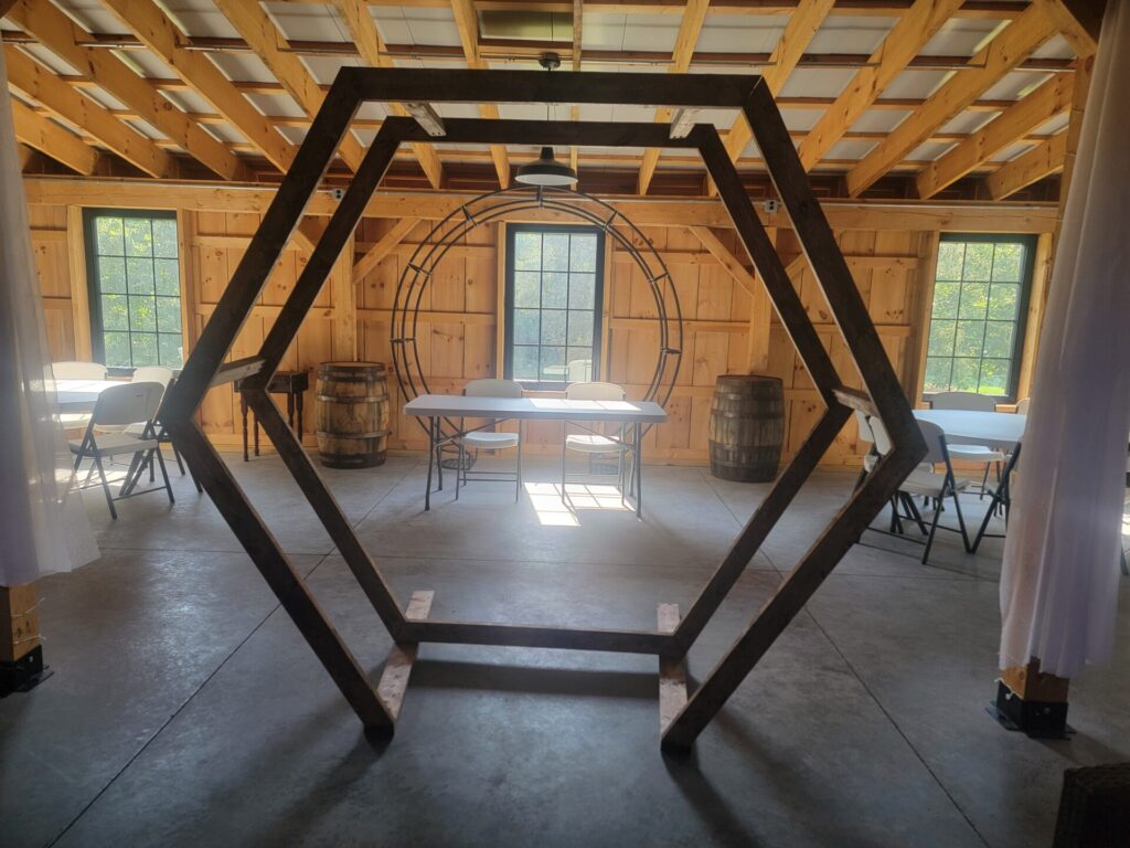 Handcrafted Hexagon Wedding Backdrop inside the timber-frame barn at Timber Valley Farm Barn Rental in Clear Spring, Maryland, shown undecorated to inspire ceremony, sweetheart table, and wedding photo backdrop ideas.