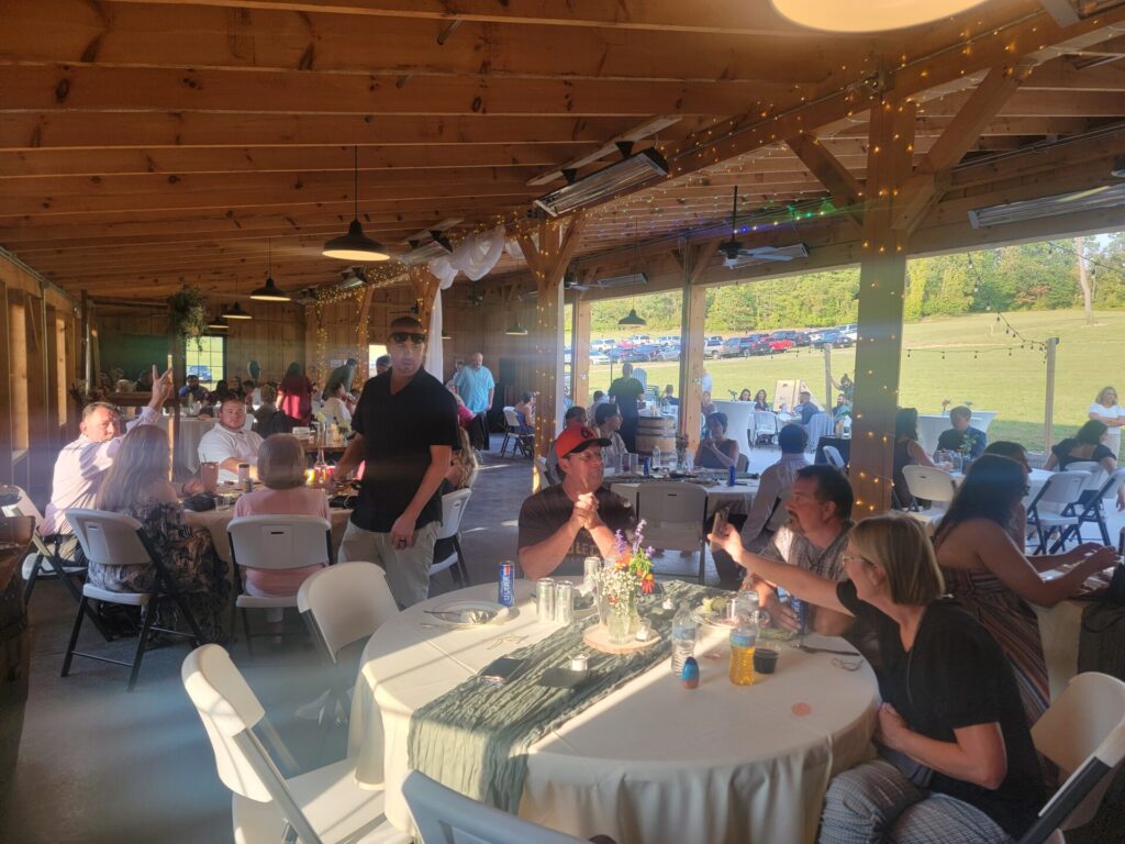 Wedding Guest Experience Maryland . Wedding guests enjoying a reception at Timber Valley Farm Barn Rental after a private marriage ceremony, gathered around tables inside the timber-frame barn
