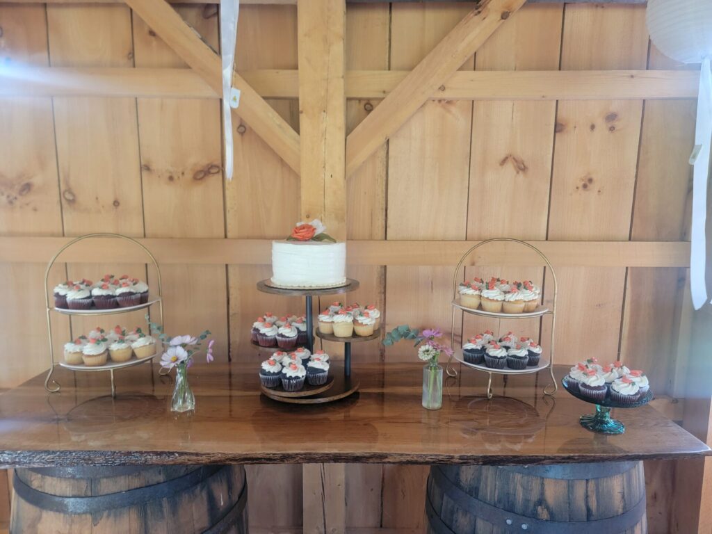 Wedding Guest Experience Maryland with wedding cake, cupcakes, flowers, and rustic dessert table at Timber Valley Farm Barn Rental