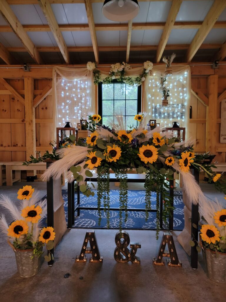 Wedding Reception Tables featuring illuminated personalized initials displayed in front of a beautifully decorated sweetheart table inside the handcrafted timber frame barn at Timber Valley Farm Barn Rental in Clear Spring, Maryland.