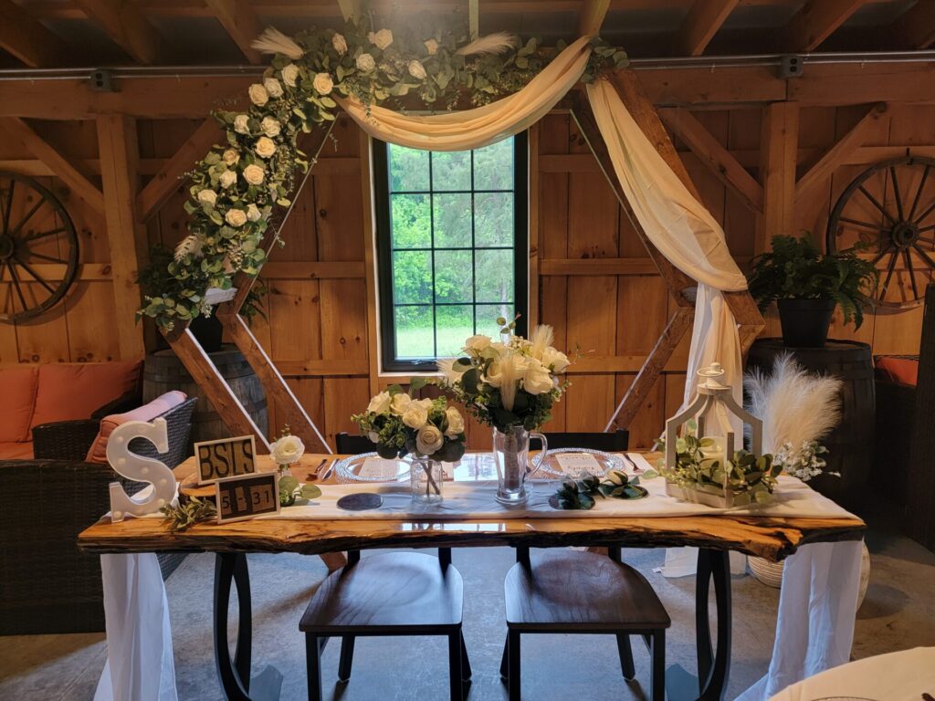 Decorated Hexagon Wedding Backdrop with a handcrafted Live Edge Sweetheart Table inside the timber-frame barn at Timber Valley Farm Barn Rental, creating a beautiful focal point for wedding ceremonies, sweetheart tables, and timeless wedding photographs.