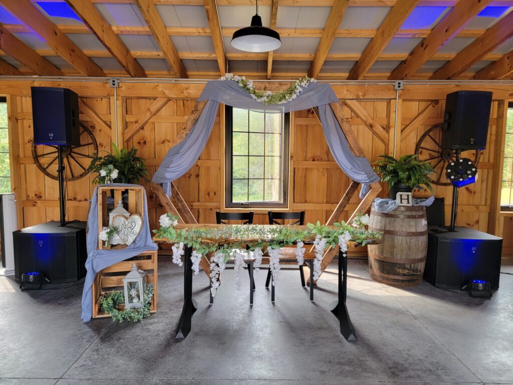 Decorated Live Edge Sweetheart Table with white floral arrangements beneath a hexagon wedding backdrop inside Timber Valley Farm Barn Rental in Clear Spring, Maryland.