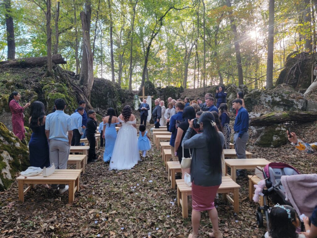 Wedding Ceremony Venue Planning at Timber Valley Farm Barn Rental in God's Cathedral with guests standing as the bride walks down the aisle.