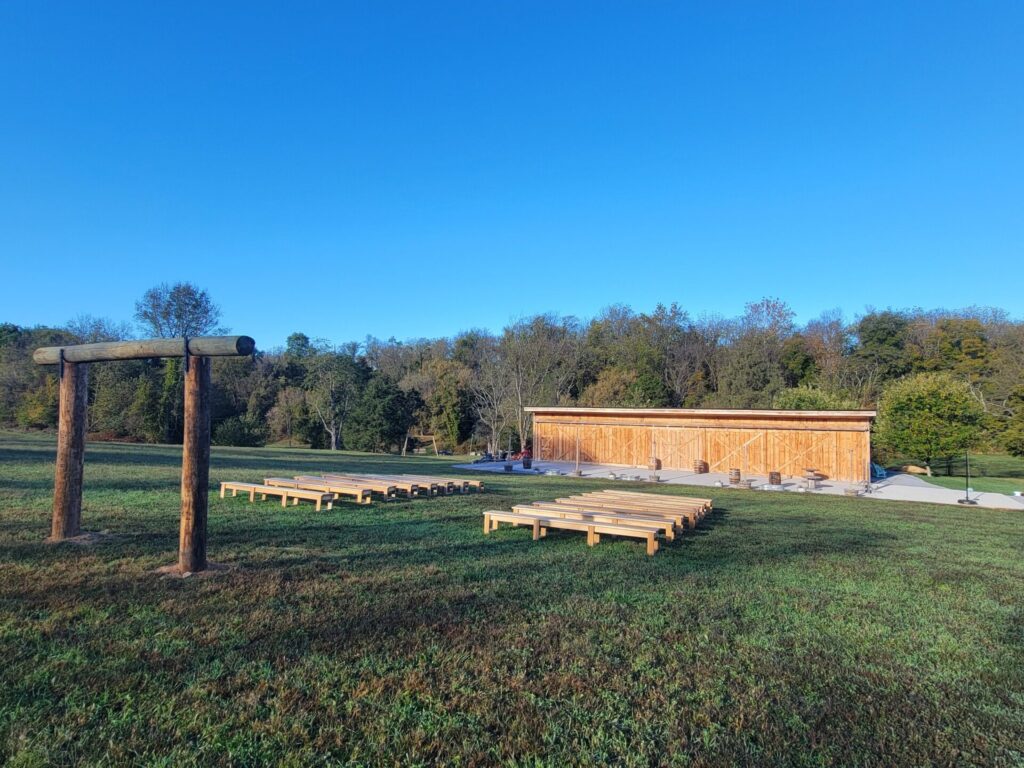 Outdoor Wedding Ceremony Ideas. Wide view of the outdoor wedding ceremony arbor, guest seating, and timber-frame barn at Timber Valley Farm Barn Rental in Clear Spring, Maryland.