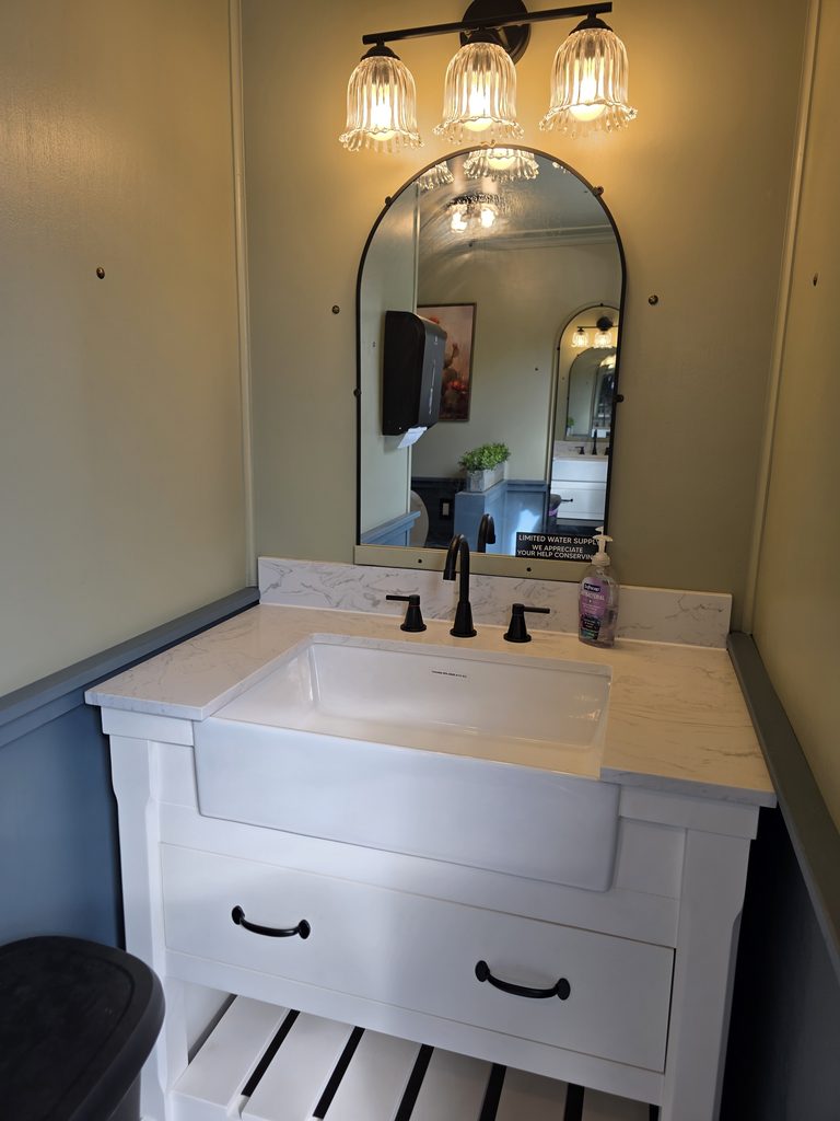 Luxury restroom trailer ladies’ vanity with modern sinks, mirrors, and decorative lighting, available as an optional wedding and event upgrade at Timber Valley Farm Barn Rental in Clear Spring, Maryland.