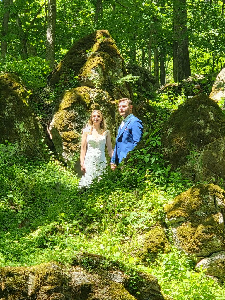 Bride and groom posing among the moss-covered boulders and lush woodland at Timber Valley Farm Barn Rental in Clear Spring, Maryland