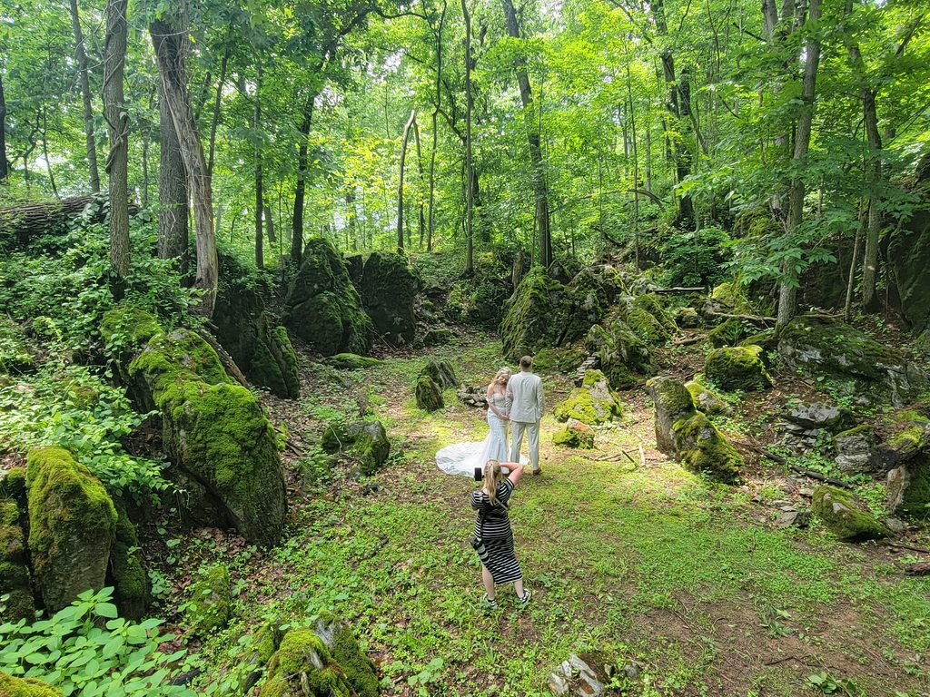 Wedding couple having portraits taken among the moss-covered boulders and woodland at Timber Valley Farm Barn Rental in Clear Spring, Maryland
