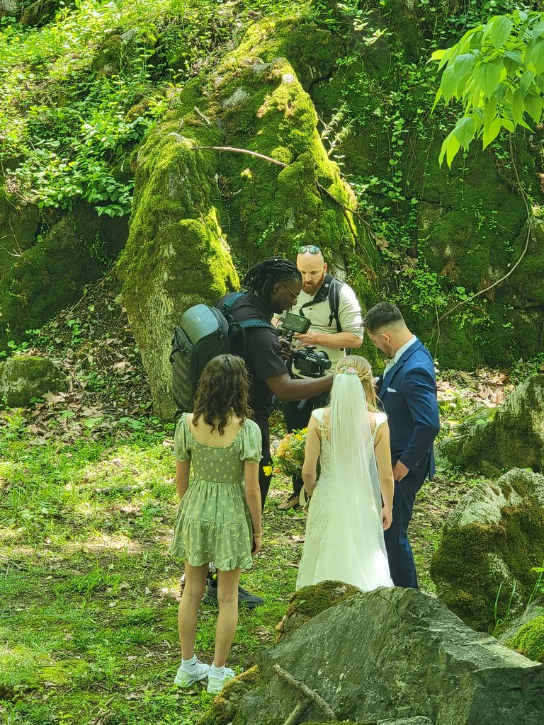 Wedding couple and photography team capturing portraits among the moss-covered boulders at The Cove at Timber Valley Farm Barn Rental in Maryland